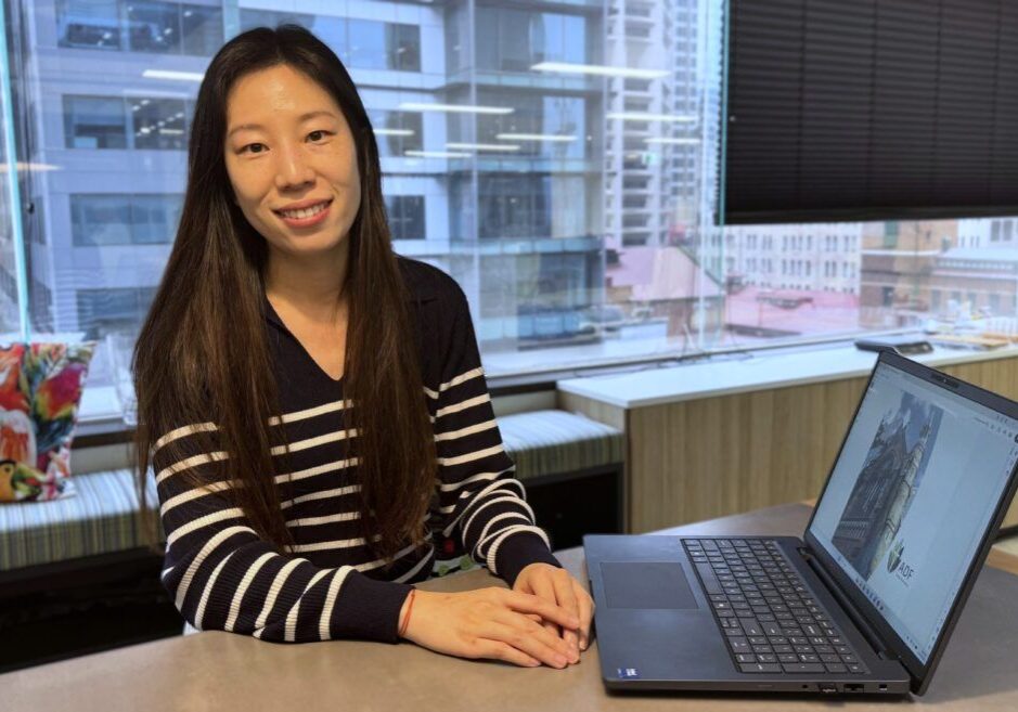 Grace smiling in the ADF office break out area in front of her laptop